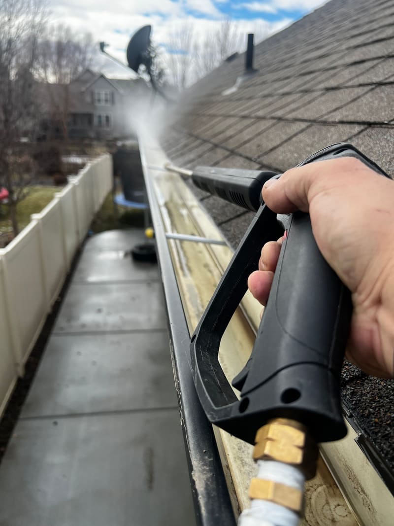 Close-up of a residential gutter being cleaned out along the roof edge.