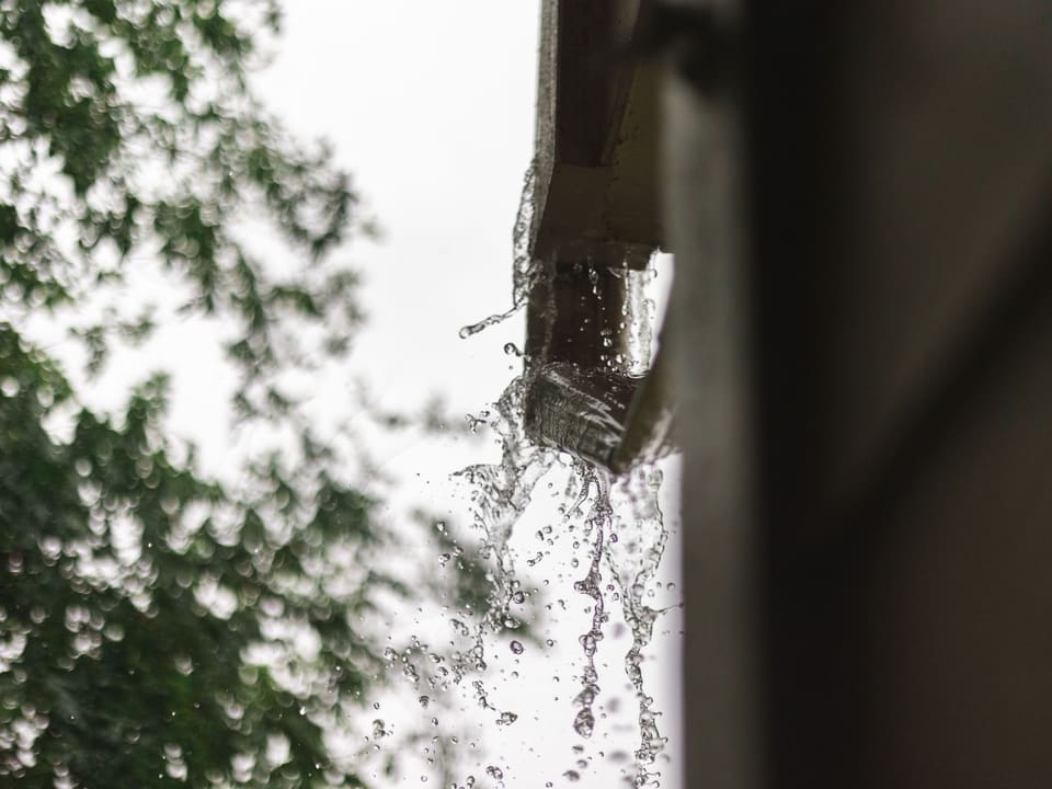 Rainwater running freely off a clear gutter during heavy rain.
