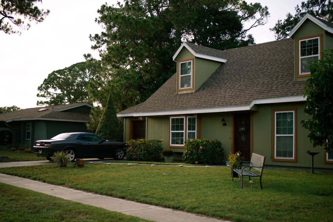 A single-story home with a mown lawn and a vehicle parked in the driveway.